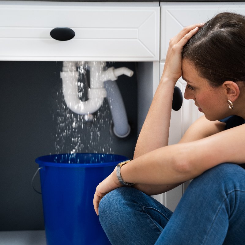 woman with a bucket under a leaking pipe