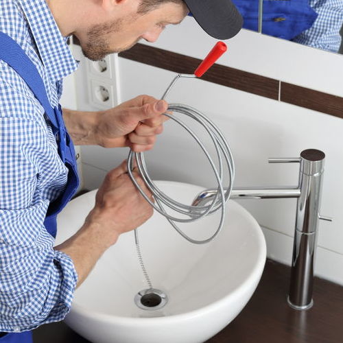 A Plumber Snakes a Bathroom Sink.