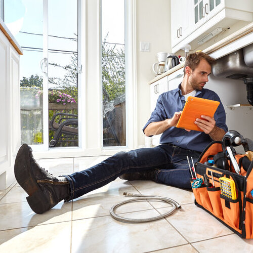 plumber checking the pipes beneath a sink