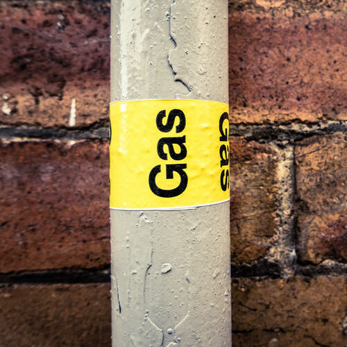 detail of a residential gas pipe against a red brick wall