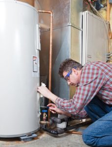 A Picture of a Man Performing Maintenance On a Water Heater